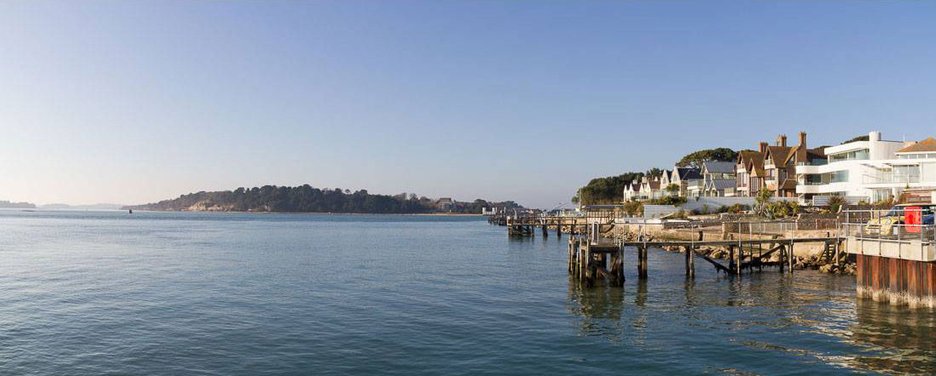 Image showing the National trust's Brownsea Island. Also see is the islands castle which is not open to the public. To the right are expensive house sitting at the edge of Poole Harbour at Sandbanks, this is often known as Millionaires Row.  The photograph was taken next to the  car and passenger ferry that works between Studland on the Isle of Purbeck and Sandbaks in Poole. 