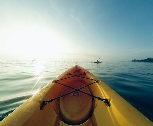 Kayaking & Canoeing in Dorset: Explore Stunning Coastlines and Serene Rivers - photo of a canoe on the sea with a headland in the distance. 